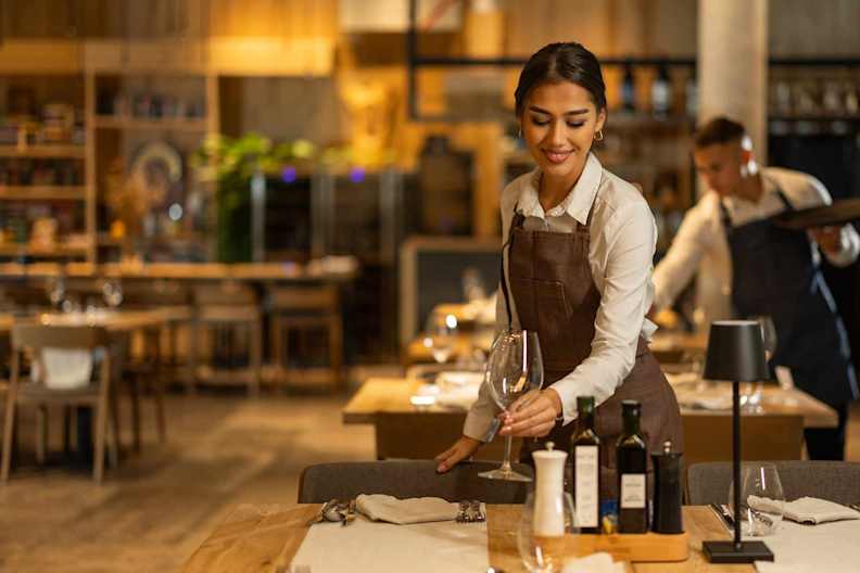 Eine Kellnerin deckt einen Tisch in einem Restaurant.