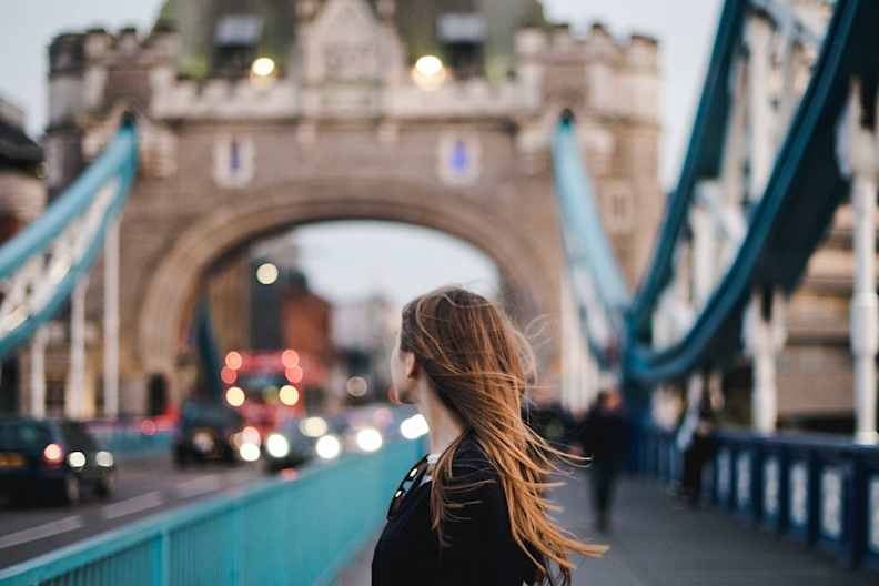 Eine junge Frau steht auf der Tower Bridge in London.