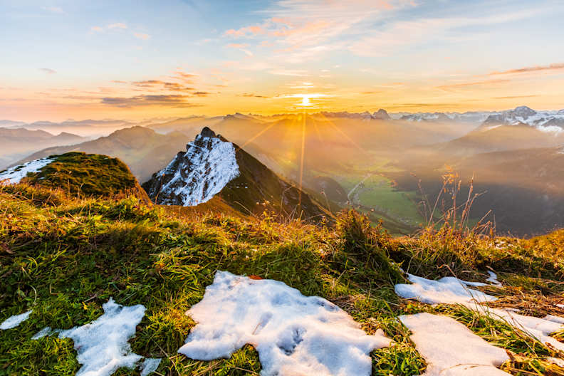 Schneebedeckte Berggipfel werden von der Sonne beschienen.