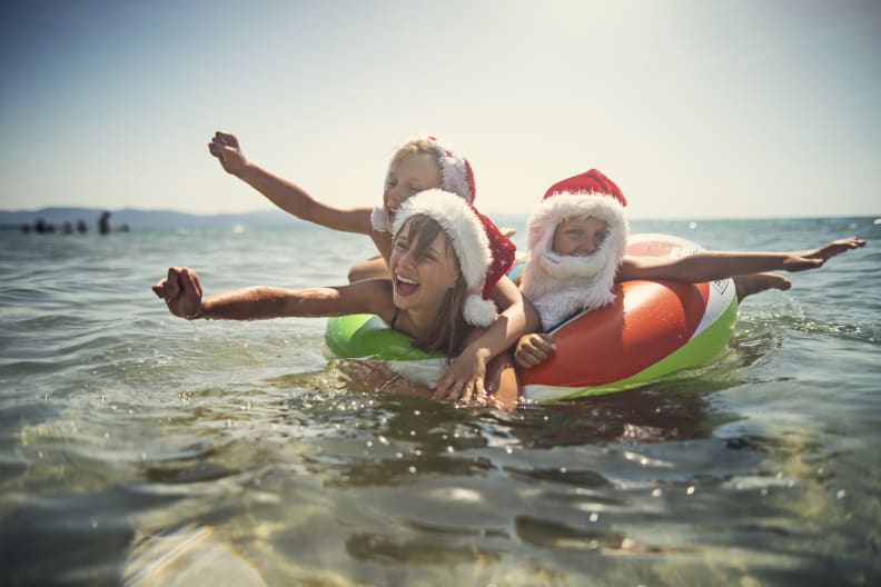 Kinder spielen im Meer auf Schwimmring im Sommer mit Weihnachtsmützen