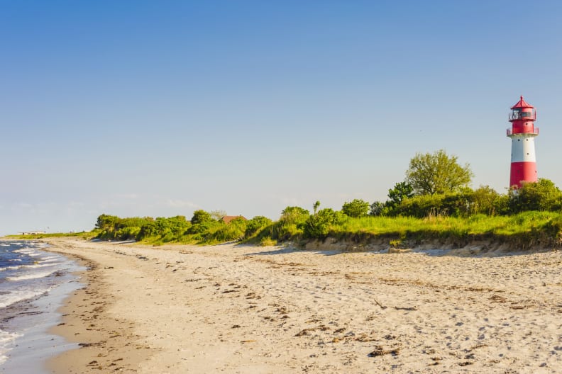 Ein Leuchtturm an einem Strand in Schleswig-Holstein, Deutschland. © Westend61/Westend61 via Getty Images