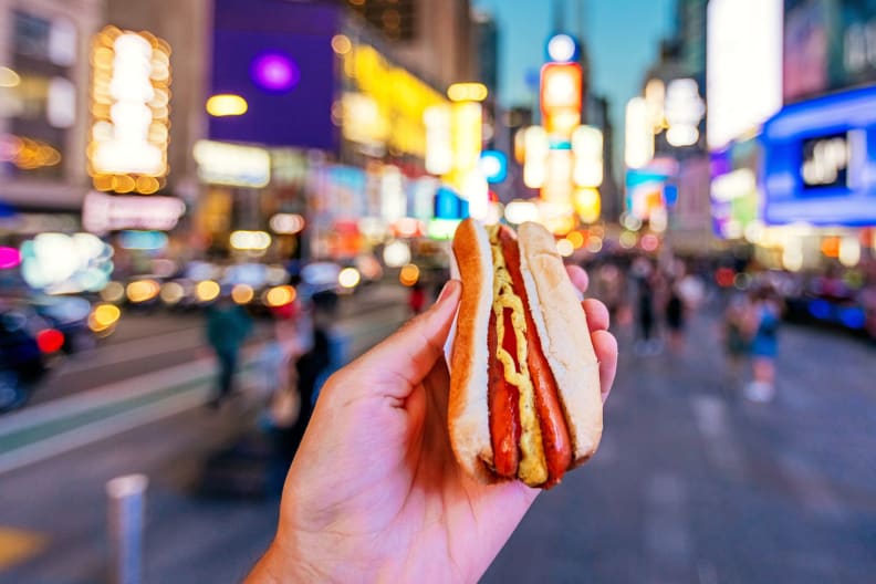 Ein Mann isst ein Hot Dog am Times Square in New York.