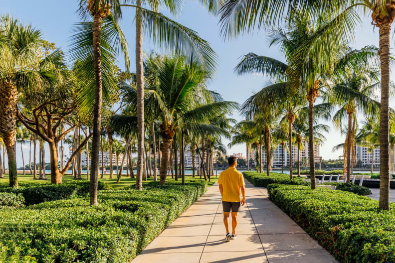 EIn Mann läuft an Palmen entlang in Miami Beach, USA.