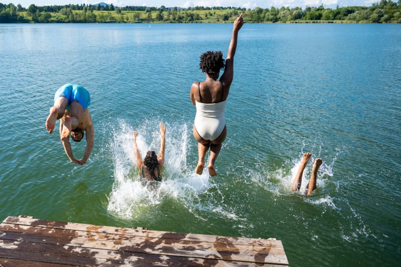 Mehrere Personen springen in das Wasser eines Sees