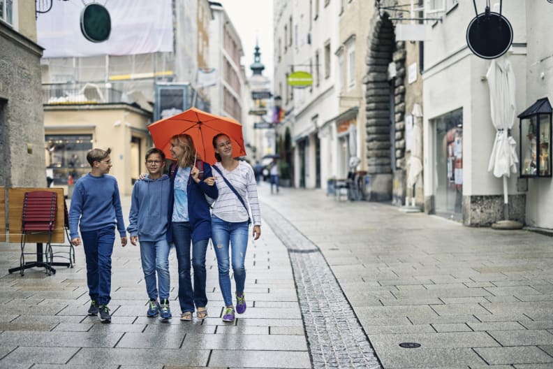 Eine Mutter läuft mit ihren Kindern im Regen durch Salzburg, Österreich. © Imgorthand/E+ via Getty Images