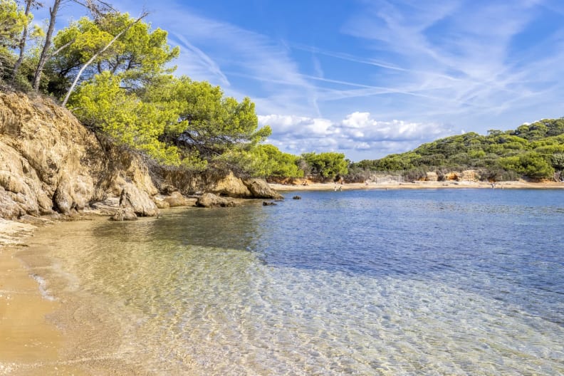 Blick auf den Strand mit Felsen im Meer auf der Insel Purquerolles, Frankreich.
