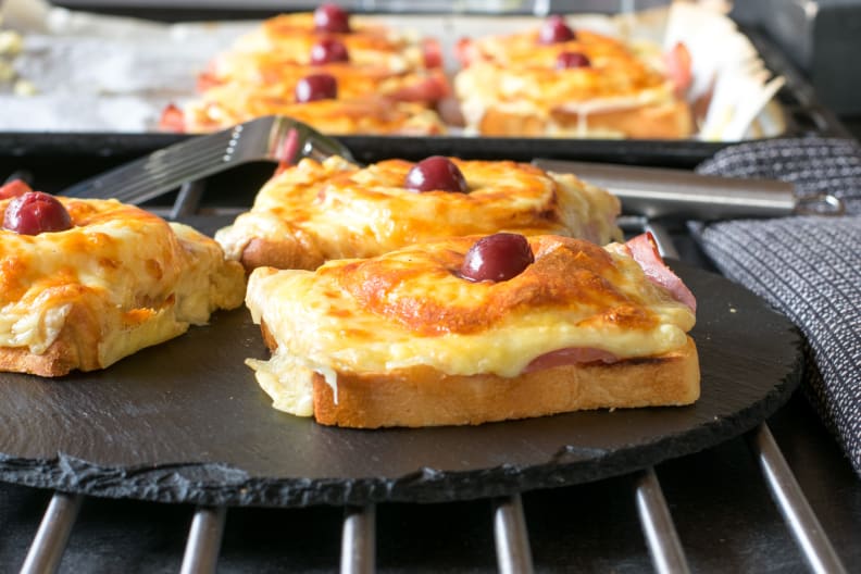 Überbackender Toast Hawaii mit Schinken, Käse und einer Kirsche.
