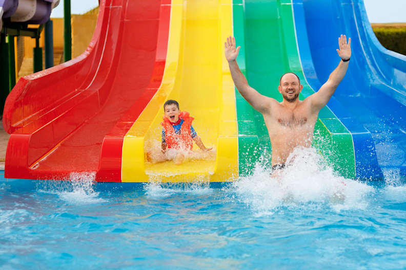 Vater und Sohn haben Spaß auf einer Wasserrutsche.