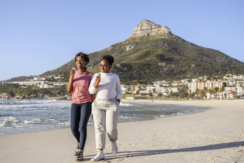 Zwei junge Frauen essen gemeinsam am Strand Eis.