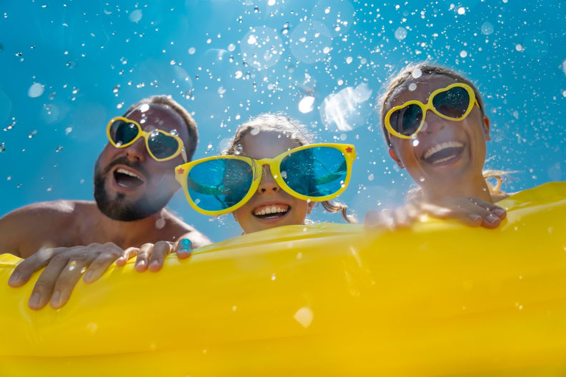 Familie hat Spaß im Wasser, alle tragen gelbe Sonnenbrillen.