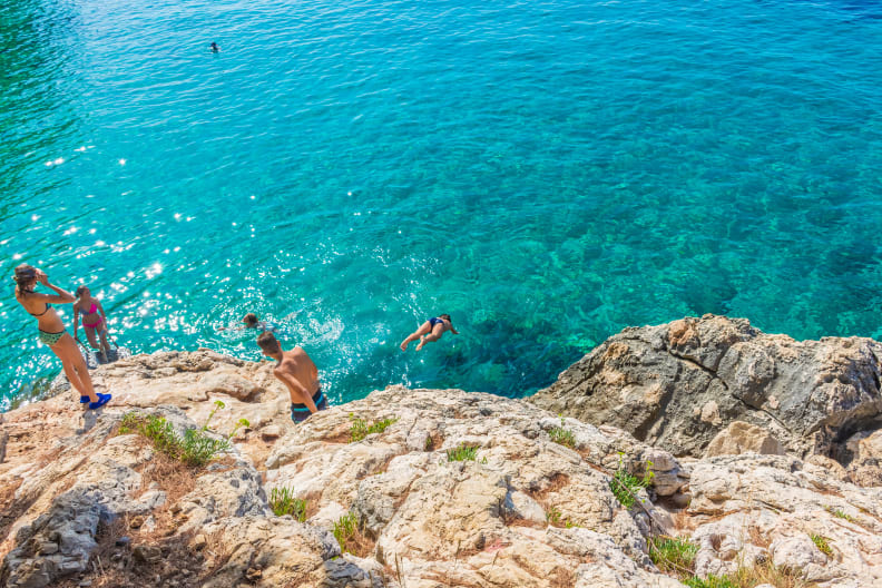 Kinder springen ins Meer von Klippen am Jagodna Beach auf der Insel Hvar, Kroatien