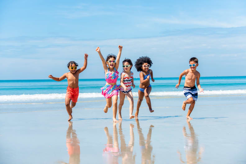 Eine fröhliche Kinderschar läuft am Strand entlang.