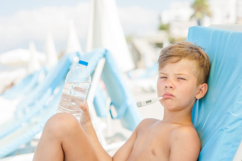 Junge mit Fieberthermometer im Mund im Urlaub.