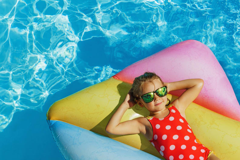 Kind liegt auf Luftmatratze im Pool.