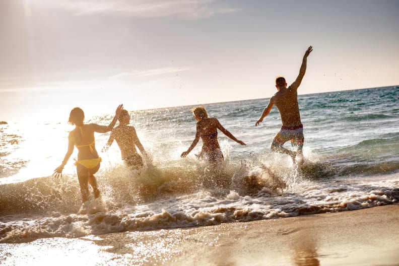 Menschen haben Spaß am Strand und laufen ins Meer.