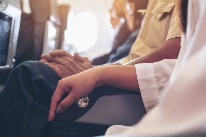 Frau und Mann teilen sich Armlehne im Flugzeug.
