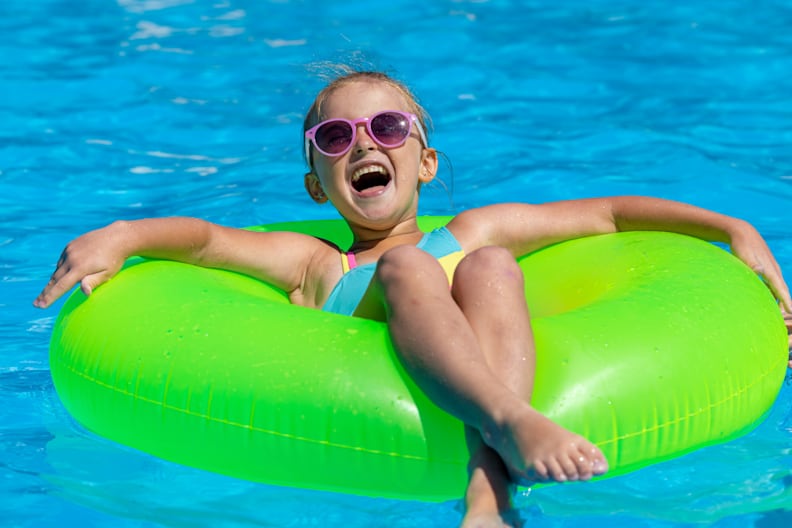 Kleines Mädchen lacht und hat Spaß auf einem Schwimmring im Pool.