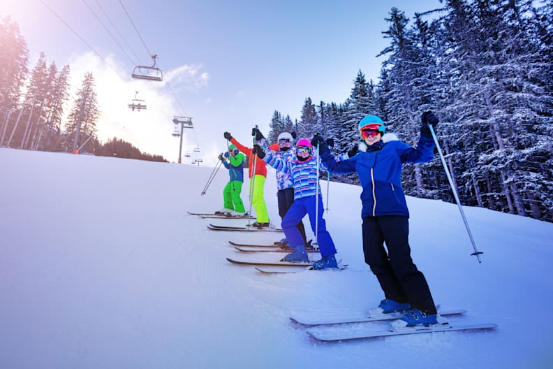 Skischüler stehen am Hang auf der schneebedeckten Piste.
