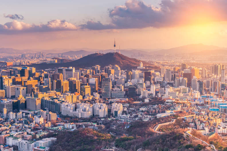 Ein Sonnenuntergang über einer Großstadt mit Bergen im Hintergrund