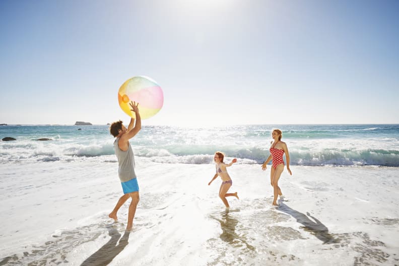 Familie spielt mit einem Wasserball am Strand © GettyImages