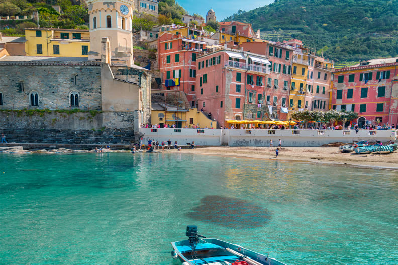 Ein Boot im blauen Wasser am Strand eines Dorfs in Cinque Terre