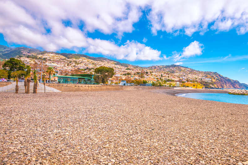 Ein Kiesstrand mit bergiger Landschaft im Hintergrund