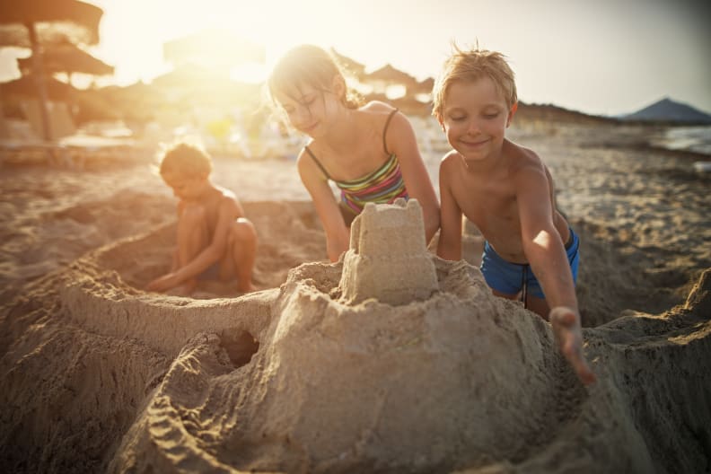 Glückliche Kinder, die eine Sandburg bauen am Strand auf Mallorca, Spanien