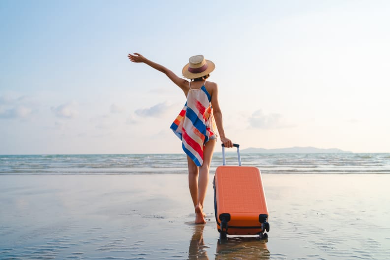 Urlauberin mit Koffer am Strand
