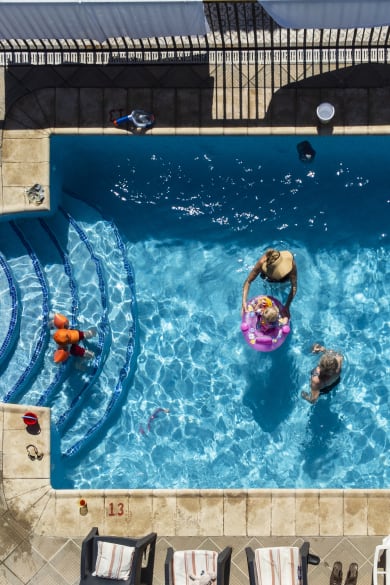 Aufnahme einer altersgemischten Familie in und um ein Schwimmbad auf Teneriffa © iStock.com/SolStock