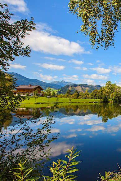 Ausblick auf den Böndlsee in Goldegg im Pongau umgeben von Wiesen, Wäldern und Bergen