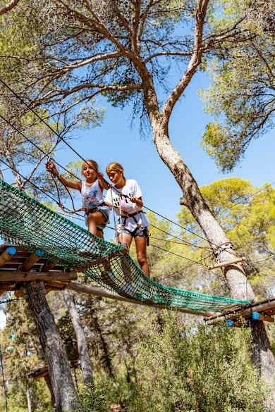 Zwei Kindern klettern in einem Kletterwald auf Ibiza