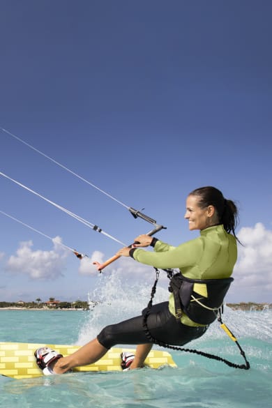 Frau hat Spass beim Kitesurfen in türkisfarbenem Meer © iStock.com/JMichl