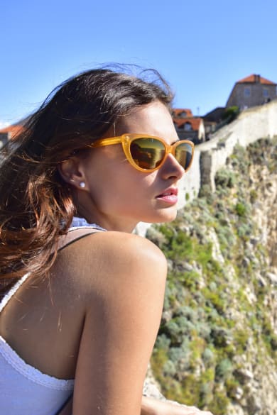 Junge Frau schaut aufs Meer mit Mauern und Häusern der Altstadt von Dubrovnik im Hintergund © iStock.com/olaser