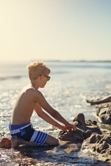 Kinder spielen am Strand und bauen eine Sandburg © iStock.com/Imgorthand