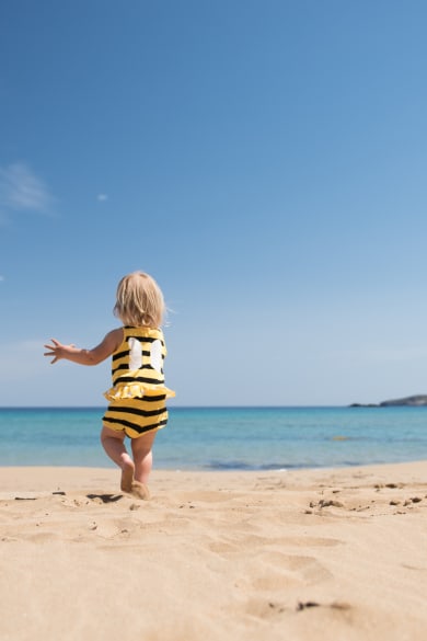 Kleines Mädchen rennt glücklich über einen Sandstrand im Urlaub © iStock.com/kamsta