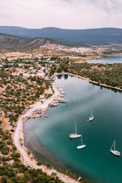 Luftaufnahme einer kleinen Küstenstadt und Segelbooten im Meer © iStock.com/AegeanBlue