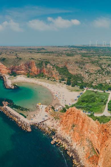 Luftaufnahme des Bolata-Strands mit geschwungener Bucht, Sandstrand und roten Klippen am Kap Kaliakra in Bulgarien