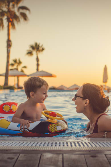 Mutter mit ihrem Kind im Pool beim Sonnenuntergang © iStock.com/ArtMarie