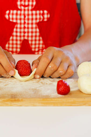 Eine Frau arbeitet Erdbeeren in Knödel ein für die süßen, fruchtigen tschechischen Knödel Ovocné knedlíky.