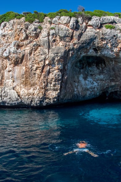 Person taucht zu einer Höhle an der Küste Mallorcas im Mittelmeer © iStock.com/Thomas Bernd
