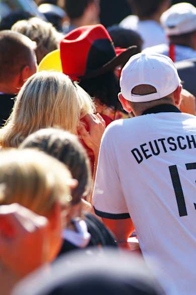 Fans in Deutschlandtrikots sitzen draußen beim Public Viewing