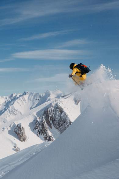 Eine Person springt mit Skiern am Berg.