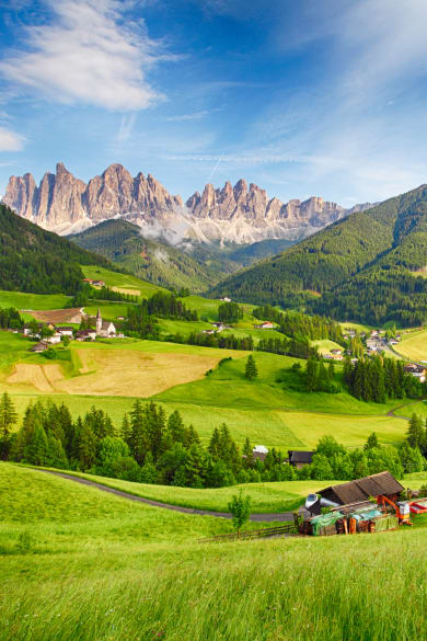 Schönes Bergpanorama mit den Dolomiten im Hintergrund und Hütten in grünem Tal © iStock.com/TomasSereda