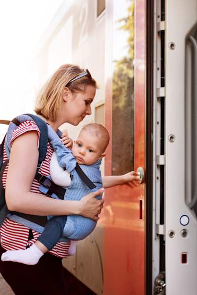 Frau mit Baby in der Trage steigt in einen Zug