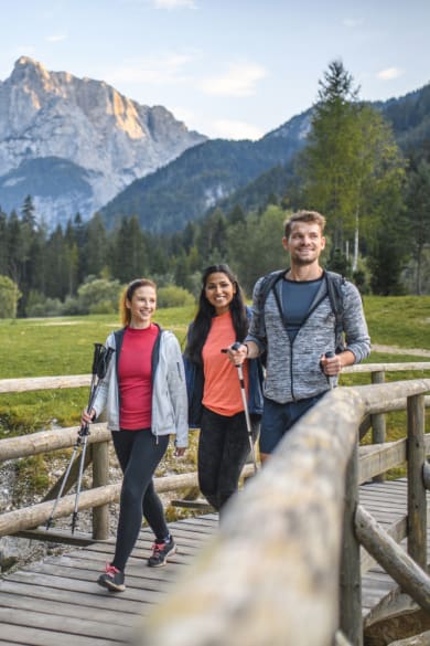 Zwei Frauen und ein Mann laufen über eine Brücke © iStock.com/AzmanL