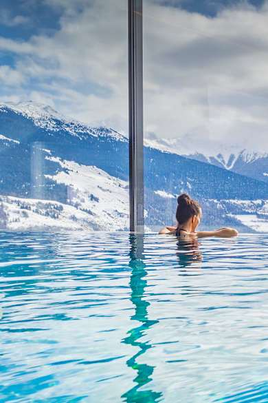 Zwei Frauen in einem Pool blicken auf eine bergige Landschaft