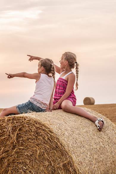 Zwei Mädchen sitzen auf einem Bauernhof.