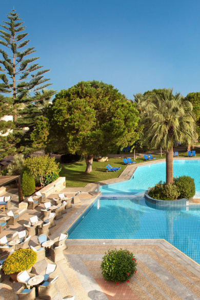 Blaues Poolbecken, Sitzmöglichkeiten, Sonnenschutz und Garten im Hotel Cretan Malia Park auf Kreta in Griechenland
