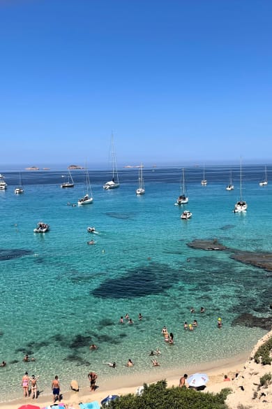 Boote und Touristinnen an der Cala Comte, Ibiza, Spanien