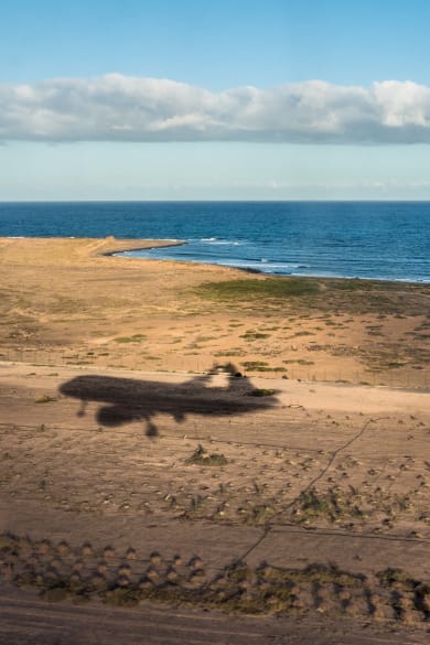 Der Schatten eines Flugzeugs über einer Küste.